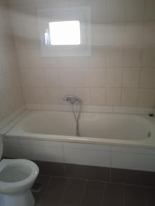 a bathroom with a tub and a toilet and a window at Ligeris house 1 in Agioi Deka in Áyioi Dhéka