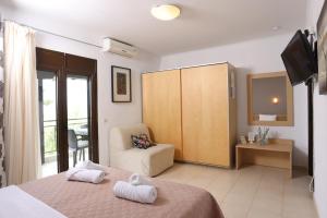 a room with two beds and a chair and a television at MaGia Peristeridi in Polychrono