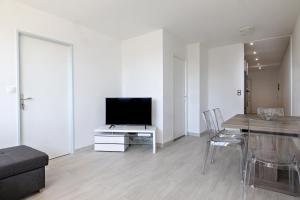 uma sala de estar com uma televisão e uma mesa com cadeiras em LE COOL LEVEL em Chalon-sur-Saône