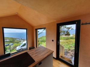 a room with three windows with a view of the ocean at Stunning 1-Bed tiny home in Isle of Skye in Elgol