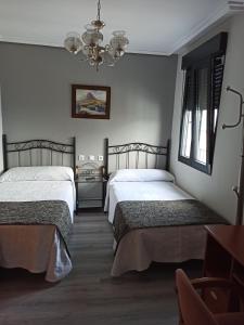 a bedroom with two beds and a chandelier at PENSION LA PARADA in Fabero