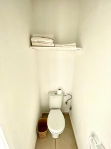 a small bathroom with a toilet with a shelf above it at Hotel Lutece in Rabat