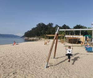 a young child is playing on a swing on the beach at Villa Playa Portomayor BUEU in Bueu