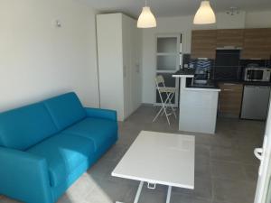 a living room with a blue couch and a white table at Studio de charme, piscine et mer à pieds in Six-Fours-les-Plages