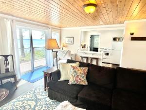 uma sala de estar com um sofá preto e uma cozinha em Private Beach - Port Ludlow Beach Cottage on Puget Sound em Port Ludlow