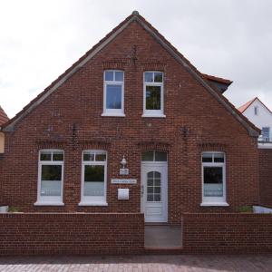 a red brick building with white windows and a door at Lüttje Hütt Mien Lüttje Hütt 01 in Norderney