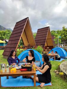 tres mujeres sentadas en una mesa de picnic frente a una tienda en Taman Bidadari wellness & Retreat, en Banyuwedang