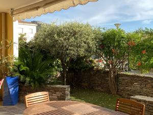 une terrasse avec une table, des chaises et des arbres dans l'établissement Le Palais Vénitien, à Saint-Cyr-sur-Mer