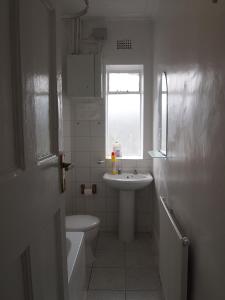 a bathroom with a sink and a toilet and a window at Paddington Flats in London