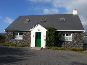 una pequeña casa de ladrillo con una puerta verde en Portmagee Seaside Cottages en Portmagee