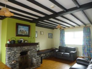sala de estar con sofá y chimenea de piedra en Portmagee Seaside Cottages, en Portmagee