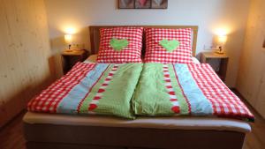 a bed with red and white blankets and pillows at BachLauf im Happy Allgäu in Leutkirch im Allgäu