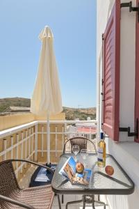 een tafel op een balkon met een fles wijn bij Akakia Residence - Vivlos Village in Vívlos