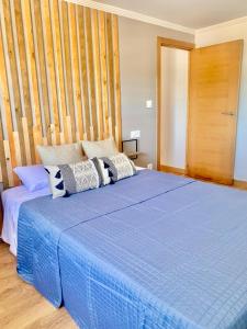 1 dormitorio con cama azul y pared de madera en Blue House - Feel The Vibe, en Vigo