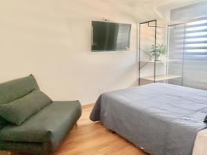 1 dormitorio con 1 cama, 1 silla y TV en Blue House - Feel The Vibe, en Vigo