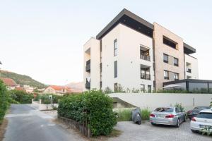 a white building with cars parked in a parking lot at Apartment Gardenija in Tivat