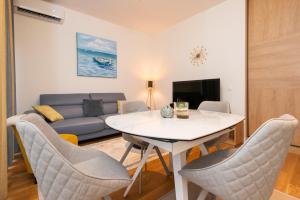 salon ze stołem, krzesłami i kanapą w obiekcie Apartment Gardenija w mieście Tivat
