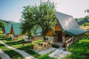 a small log cabin with a table and a tree at Apartmani i kuće Moje selo Šćepanović in Kolašin