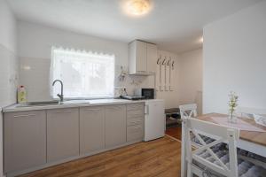 a kitchen with white cabinets and a table and a window at Apartmán pod čerešňou in Banská Štiavnica