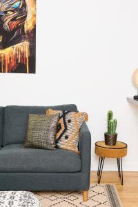een blauwe bank in een woonkamer met een cactus bij Appartement Wakandais-proche Disney, parking & wifi in Montévrain
