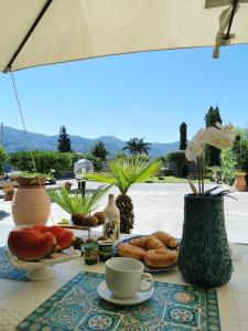 una mesa con pastas y tazas y una sombrilla en B&B Atrium, en Pompeya