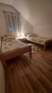 two beds in a room with wooden floors at Apartment Slap in Rakovica