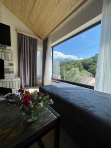 a bedroom with a large window with flowers on a table at Dili guest house in Dilijan