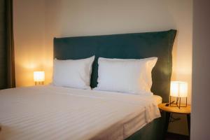 a bed with a green headboard and two lamps on tables at Luxury Art 4 Apartment in Blagoevgrad