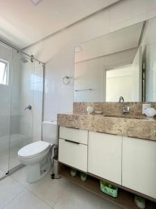 Un baño con inodoro, lavabo y espejo. en Apto 80m da Praia Grande vista mar!, en Governador Celso Ramos