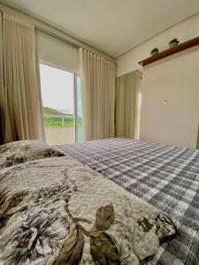 Un dormitorio con una cama con una colcha encima en Apto 80m da Praia Grande vista mar!, en Governador Celso Ramos