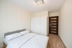 sypialnia z białym łóżkiem i drewnianą podłogą w obiekcie Metro Kondratowicza Spacious Apartment w Warszawie