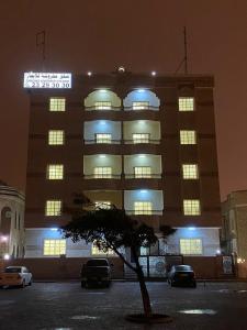 un edificio con coches aparcados delante de él por la noche en AL KALDi, en Salalah