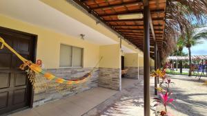 a building with a porch with a hammock hanging from it at Arena Carneiros Hotel by AFT in Tamandaré