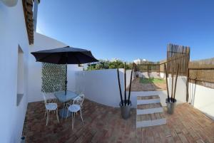 a patio with an umbrella and a table and chairs at Alma N' Sleep in Almancil