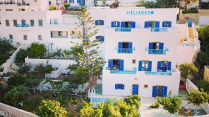 an aerial view of a white building with blue windows and a tree at HELIADES SUITES in Panteli