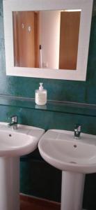 y baño con espejo y 2 lavabos blancos. en Albergue o Apalpador, en Melide