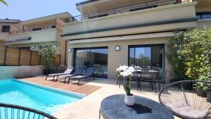 Casa con piscina, mesa y sillas en Villa 4 chambres piscine privée à 400m de la plage dans une résidence neuve en Conca