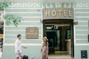 a man and a woman pulling a suitcase outside a hotel at Piedra de Agua Hotel Boutique Mérida in Mérida +56 photos