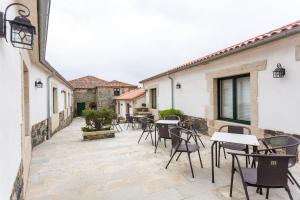 eine Terrasse mit Tischen und Stühlen im Innenhof in der Unterkunft Casa da Ponte de Penas in Melide