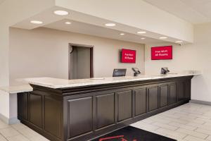 a reception counter in a hospital with red signs on the wall at Red Roof Inn Gulfport - Biloxi Airport in Gulfport