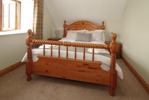 a bedroom with a wooden bed with white pillows at Parkfields Barns Self Catering Accommodation in Buckingham