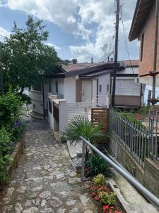 a house with a fence and a stone walkway at Stojanoski Studios & Rooms in Trpejca