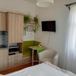 a bedroom with a bed and a desk and a tv at Bíbic Apartman C in Kápolnásnyék