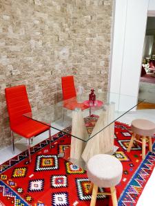 a glass table and two red chairs and a rug at Kabana Suite Thessaloniki in Thessaloniki