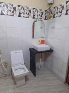 La salle de bains est pourvue de toilettes blanches et d'un lavabo. dans l'établissement ISKCON Hare Krishna Homestay, à Vrindavan