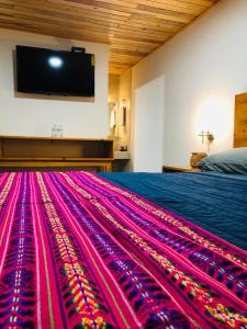 a room with a bed with a colorful carpet at Hotel Mar&iacute;a del T&iacute;o Molcas in Creel