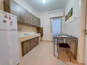 eine Küche mit einem Tisch und einem weißen Kühlschrank in der Unterkunft DEL MAR APARTMENTS I in Agía Triás