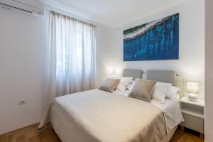 a bedroom with a white bed with a blue painting on the wall at MAR Sea View Apartment in Supetar