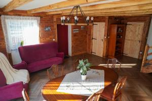 ein Wohnzimmer mit einem Tisch und einem lila Sofa in der Unterkunft Domek na Kaszubach przy lesie i wodzie, Załakowo, Na Gwizdówce, Różany Domek II Kaszubska Wenecja in Pałubice