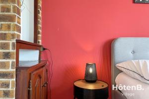 - une chambre avec un mur rouge et une lampe à côté d'un lit dans l'établissement Grande maison de 140 m2 avec jardin ! 5 chambres, à Limoges